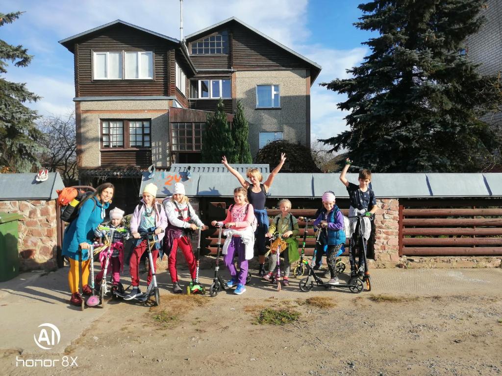 a group of children on scooters in front of a house at Aghrougolok Hostel in Lida