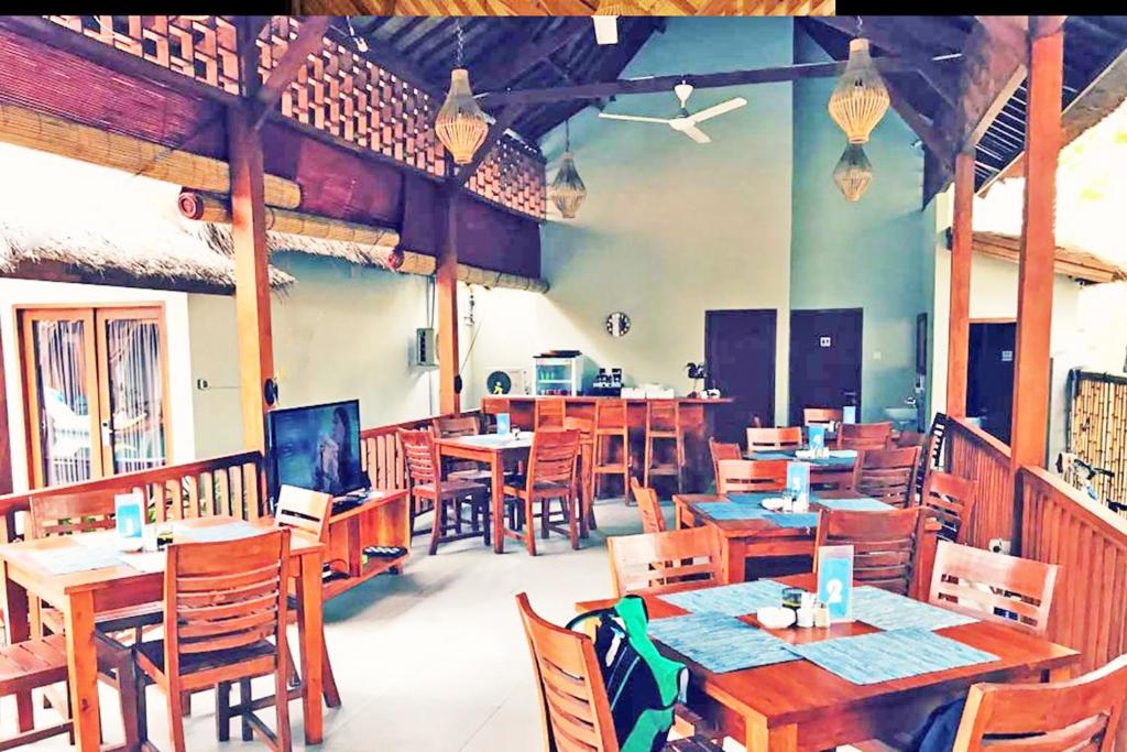 un ristorante con tavoli e sedie in legno di Gili One Resort a Gili Trawangan