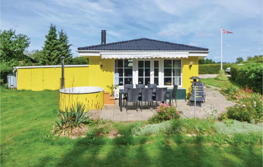 a yellow house with a table and chairs in a yard at Two-Bedroom Holiday Home In Broager in Broager