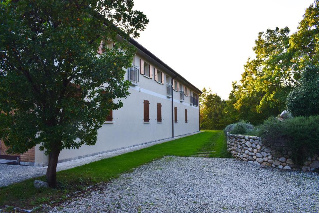 um edifício branco com uma árvore e uma parede de pedra em BeeHouse - La Casa delle Api Agriturismo em Borso del Grappa