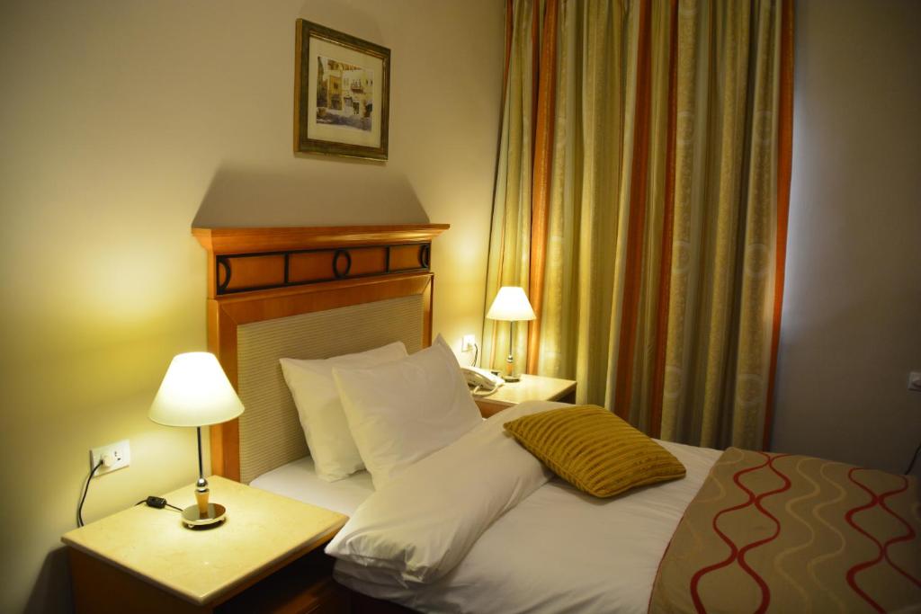 a hotel room with a bed and a table with a lamp at The Y Hotel in Amman