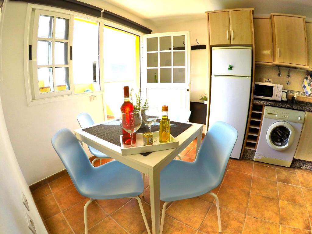 a kitchen with a table with chairs and a refrigerator at Apartamentos Ester in Santa Cruz de Tenerife