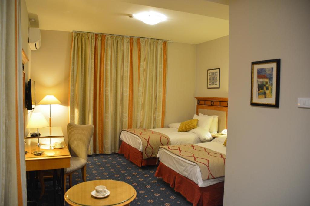 a hotel room with two beds and a desk at The Y Hotel in Amman