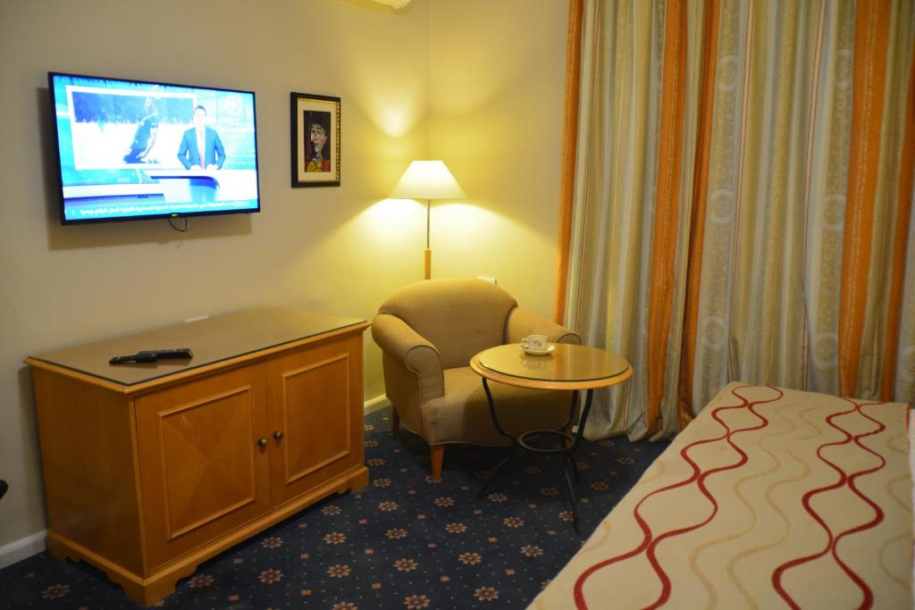 a hotel room with a bed and a tv and a chair at The Y Hotel in Amman