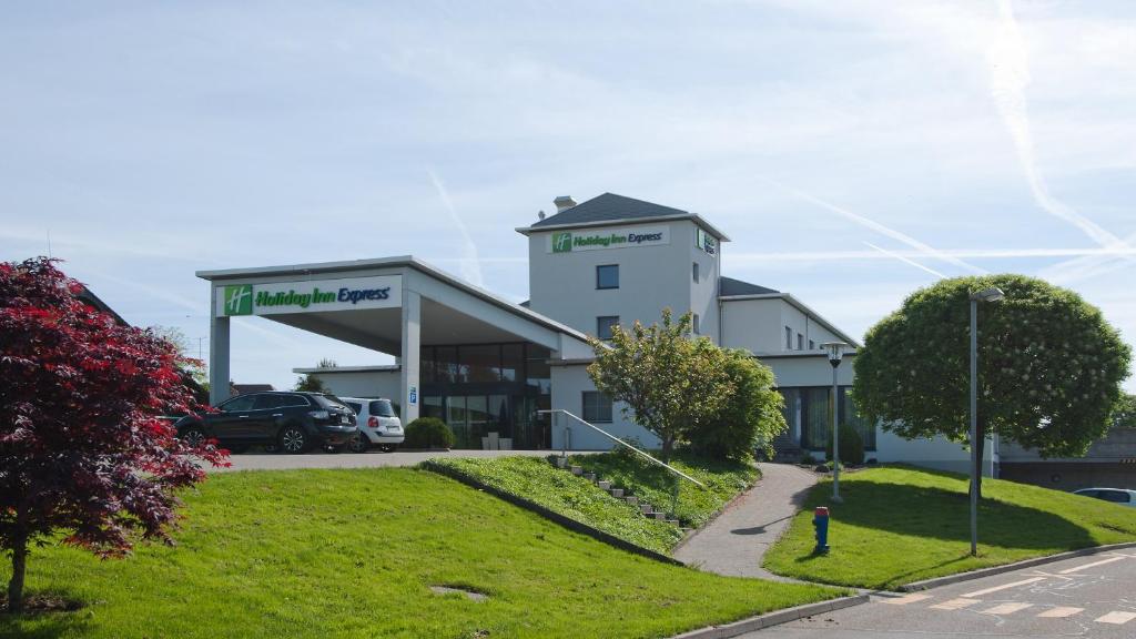 a large white building with a car dealership at Holiday Inn Express Luzern-Neuenkirch, an IHG Hotel in Rothenburg