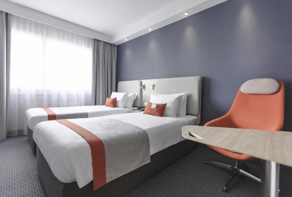 una camera d'albergo con due letti e una sedia di Holiday Inn Express Luzern-Neuenkirch by IHG a Rothenburg