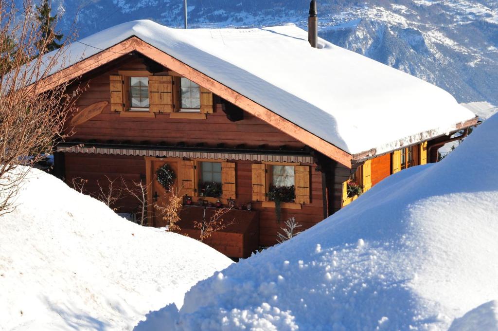 a house covered in snow with a pile of snow at Chalet Mon Rêve in Savièse