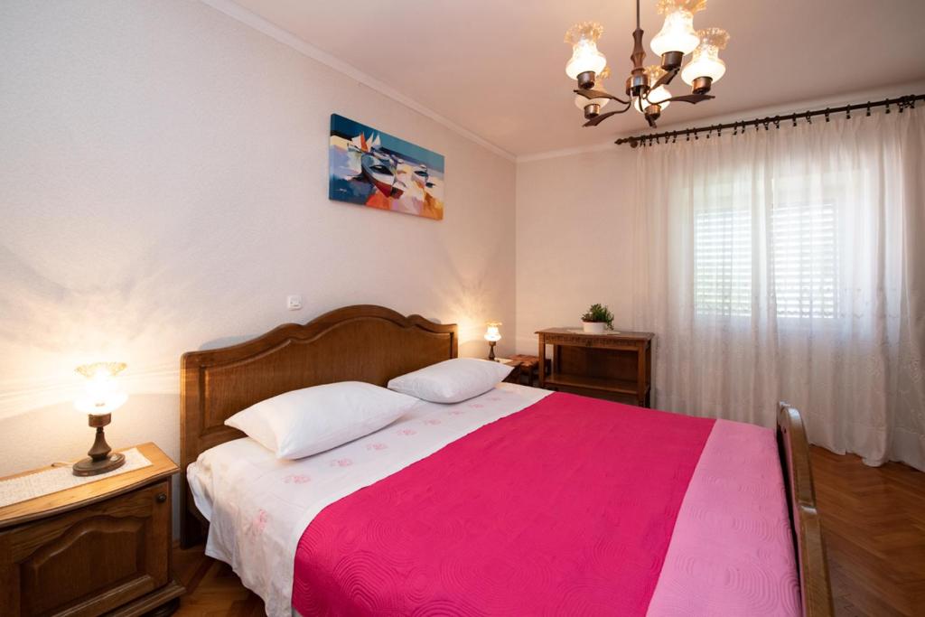 a bedroom with a large bed with a pink blanket at Vacation home, Ferienhaus KLAUDIA in Kraj, Mošćenička Draga near Opatija in Mošćenička Draga