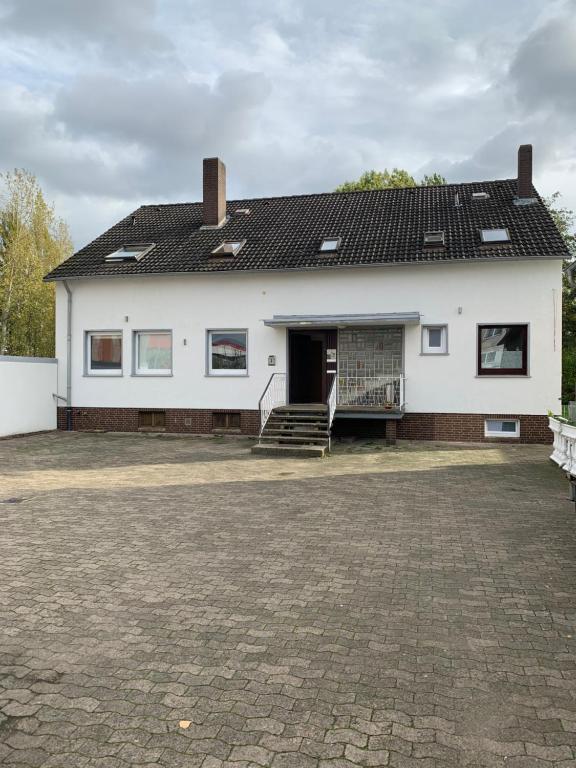 une maison blanche avec une terrasse couverte et un escalier dans l'établissement Apartment First Floor Laatzen, à Hanovre