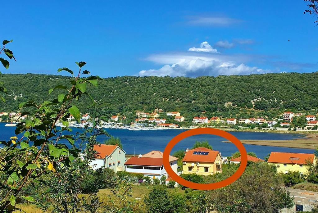 a house with an orange circle in front of a body of water at Jaška Anica Apartments in Supetarska Draga