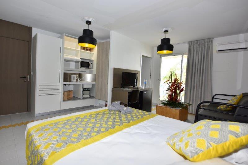 a bedroom with a large bed with a yellow blanket at Studio Methys des Iles -Manganao Saint françois 971 in Saint-François