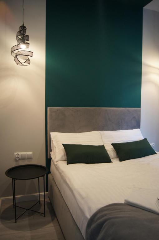 a bedroom with a large bed with a green wall at Green Park Apartament in Toruń