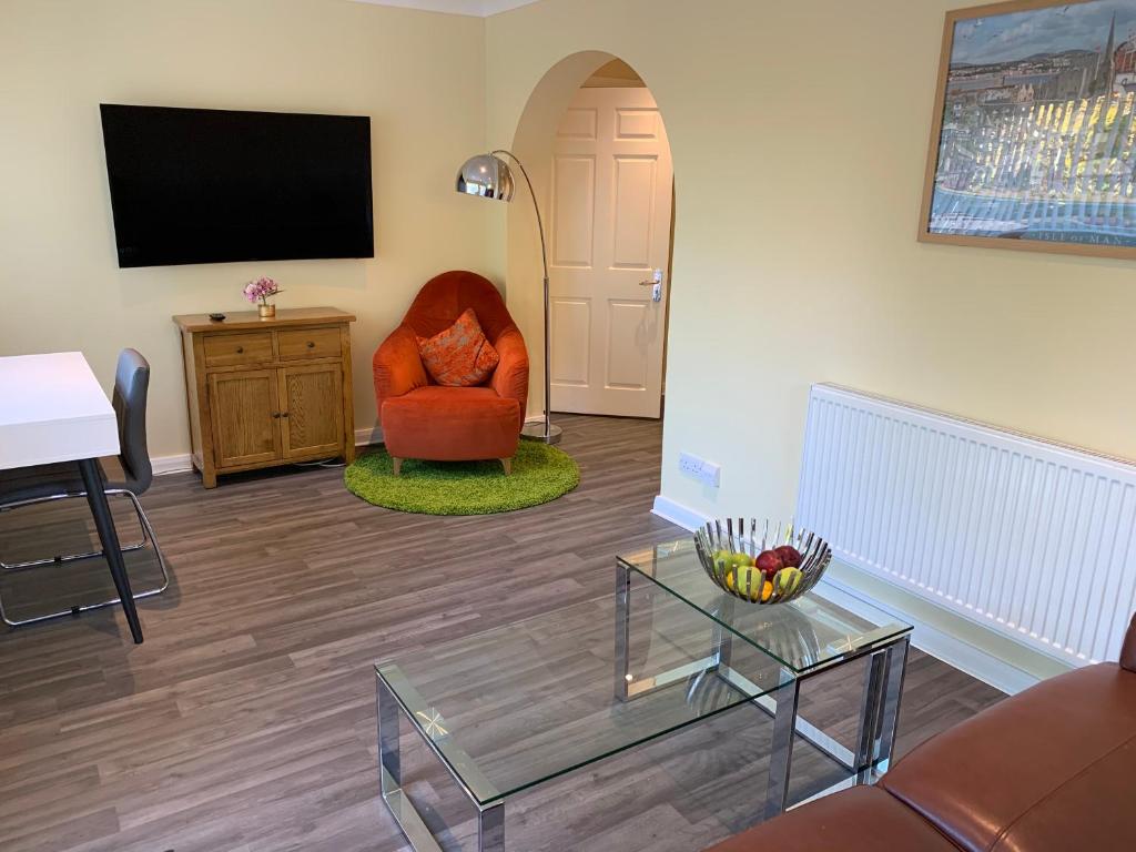 a living room with a red chair and a television at The Firs - Moorside Annexe in Douglas