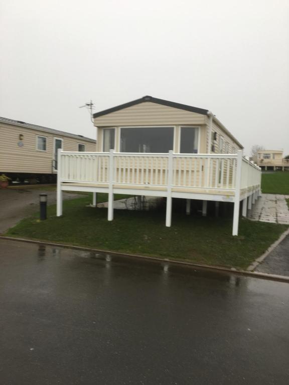 uma casa com um deque branco na relva em Caravan Hire Crimdon Dene Holiday Park em Durham