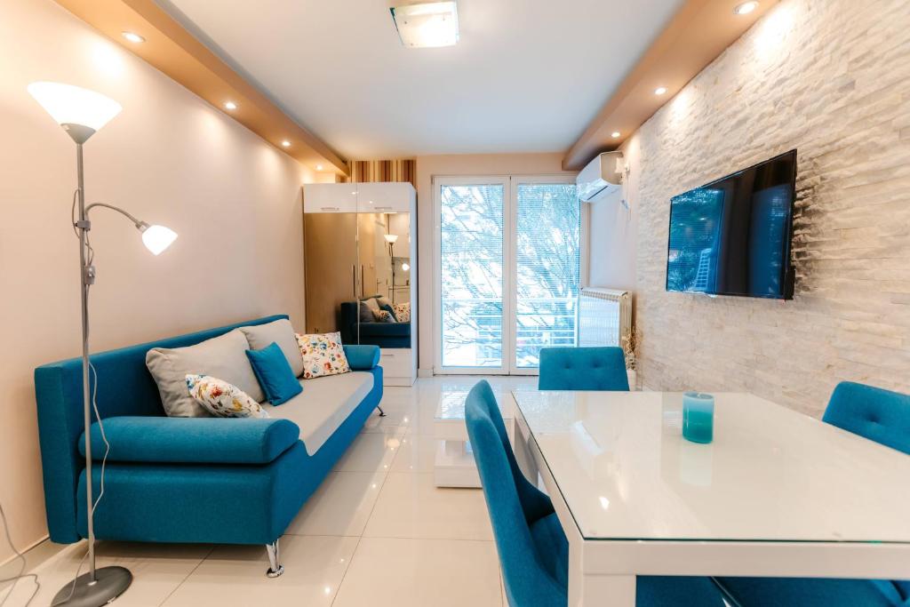 uma sala de estar com um sofá azul e uma mesa em Turist Apartment em Niš