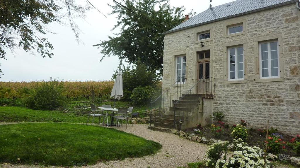ein altes Steinhaus mit einem Tisch und einer Terrasse in der Unterkunft La Layotte in Vosne-Romanée