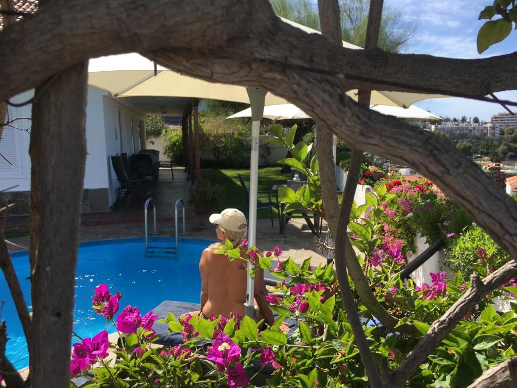 Ein Mann, der neben einem Pool mit Blumen sitzt. in der Unterkunft Casa Janni in Puerto de la Cruz