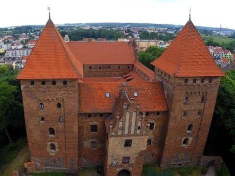 un grand bâtiment en briques avec des toits orange dans l'établissement Zamek Nidzica, à Nidzica