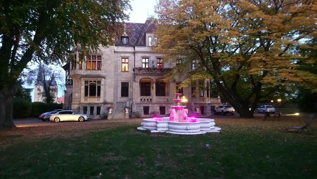 einen Brunnen im Gras vor einem Gebäude in der Unterkunft Schlosshotel zum Markgrafen in Quedlinburg