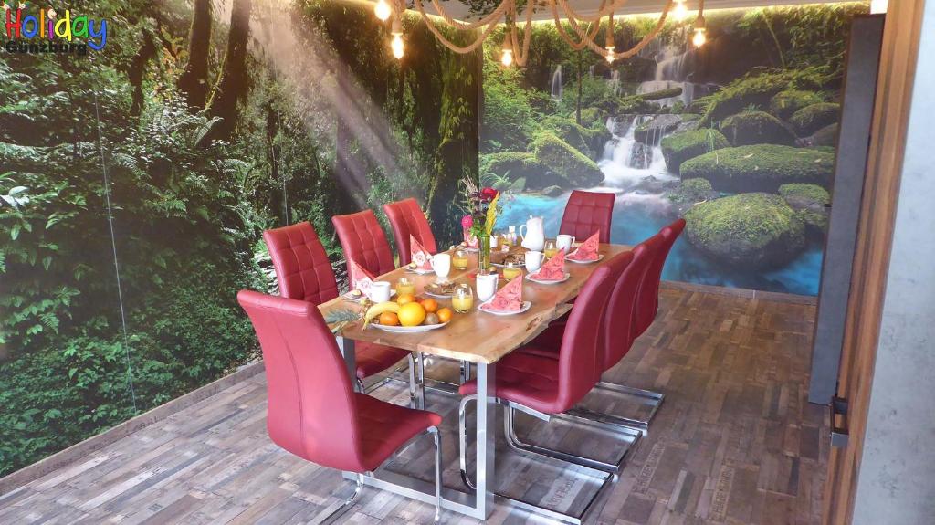 una mesa de comedor con sillas rojas y una cascada en Ferienwohnung Jungle Adventure, en Günzburg