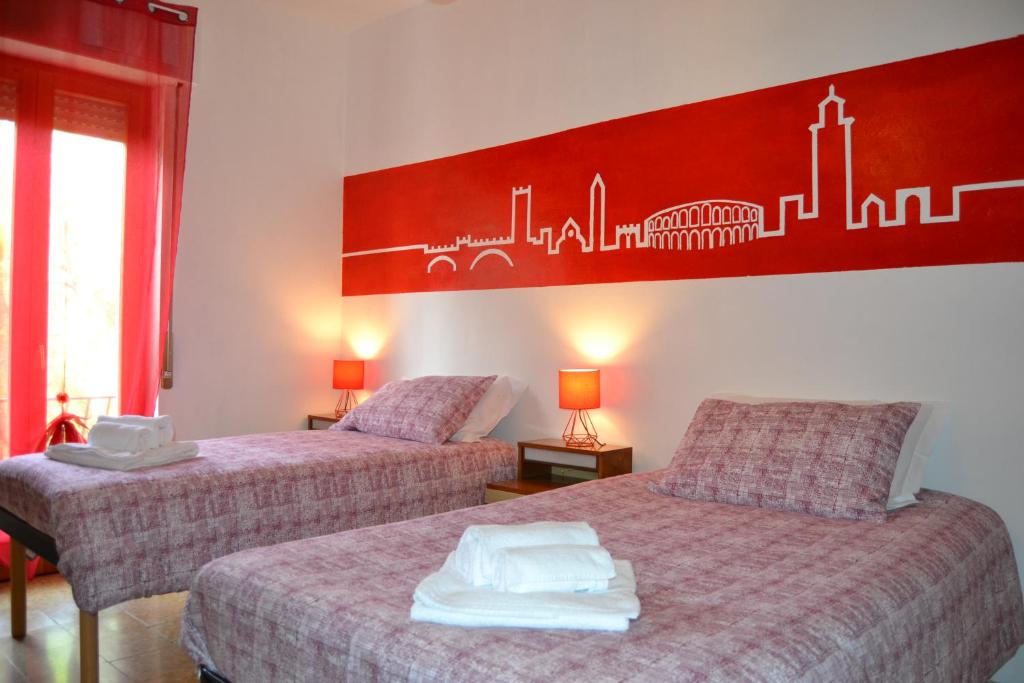 two beds in a room with a red painting on the wall at Da Fabio e Francesca - Holiday Apartment in Verona