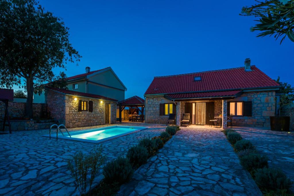 a villa with a swimming pool in front of a house at Rural House Gluic in Bogatić