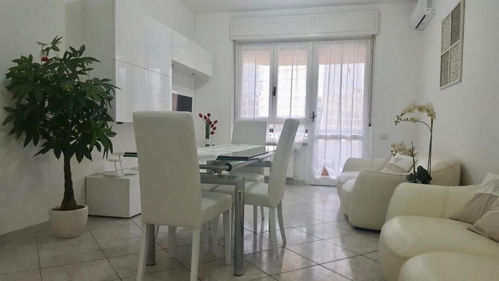 a living room with a table and white chairs at Elena’s home in Cagliari