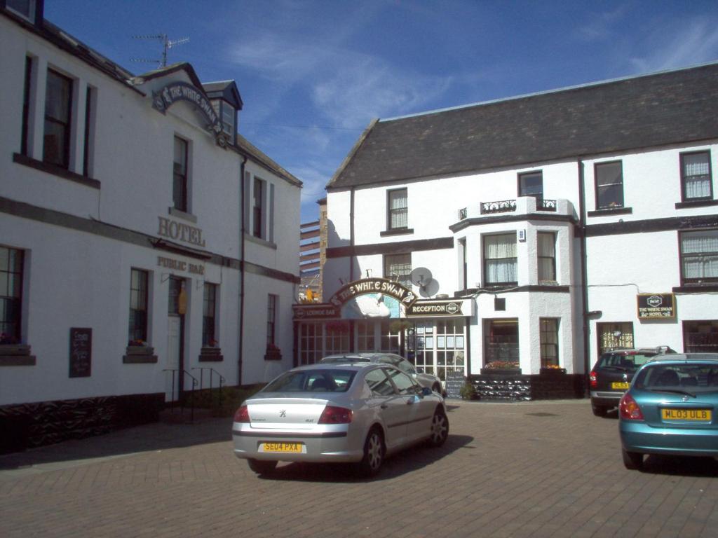 un grupo de coches estacionados frente a los edificios en The White Swan Hotel, en Duns