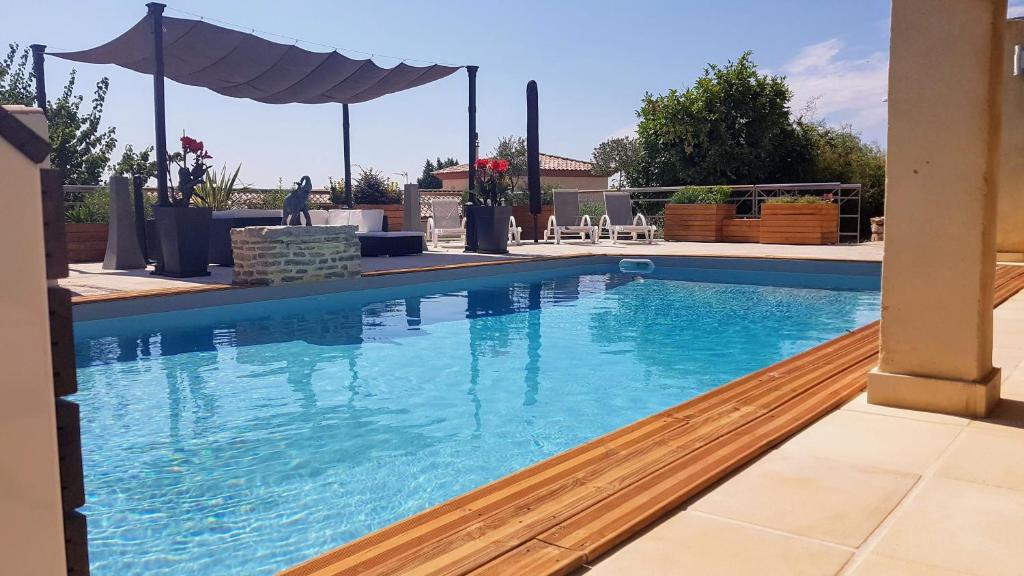 - une piscine d'eau bleue avec un parasol dans l'établissement Gîte d'Emma, à Lauret