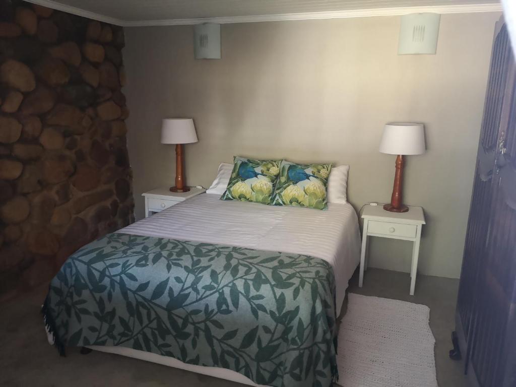 a bedroom with a bed and two lamps on two tables at Arend Cottage in Nelspruit
