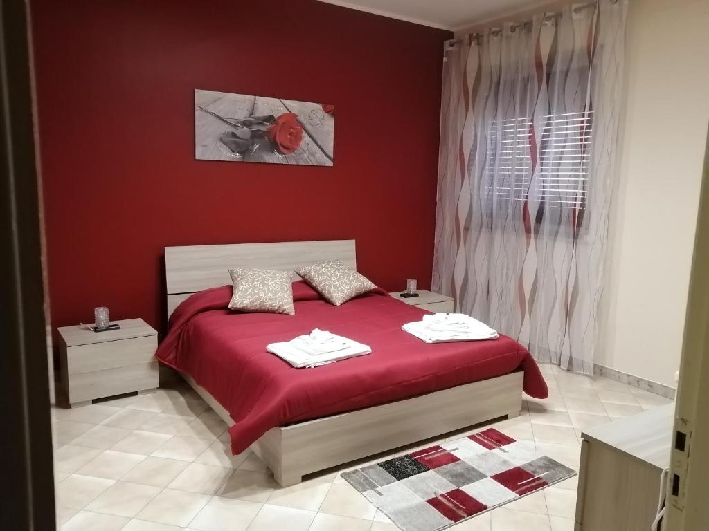 ein rotes Schlafzimmer mit einem Bett und einer roten Wand in der Unterkunft Casa vacanza Petrulli in Zafferana Etnea