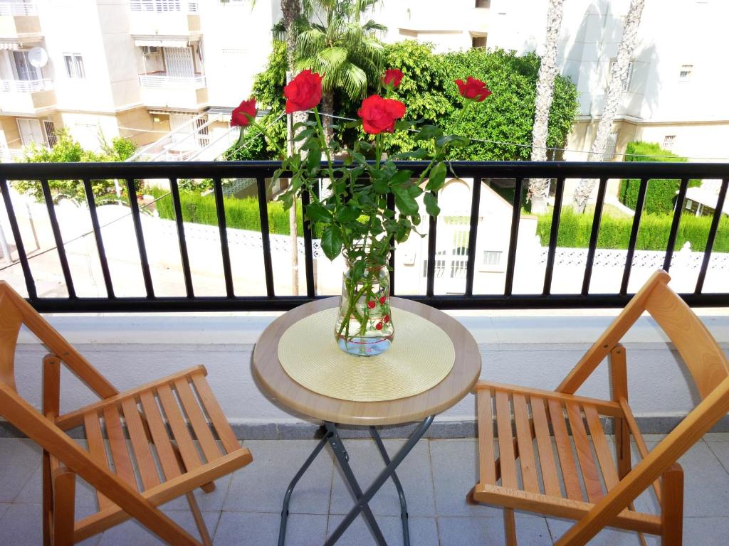a table with a vase of flowers and two chairs at The cozy apartment in Torrevieja