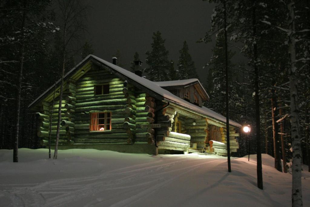 una cabaña de madera en la nieve por la noche en Viprakka, en Levi