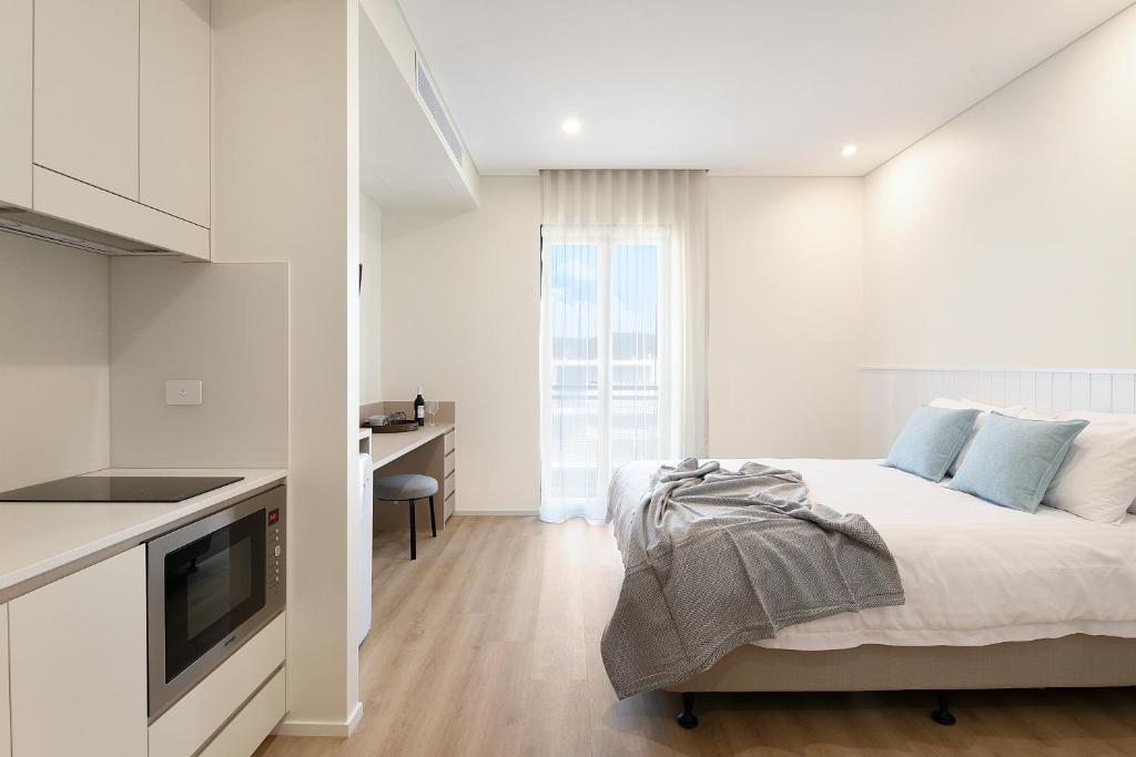 a white bedroom with a bed and a desk at Nova Kiama in Kiama