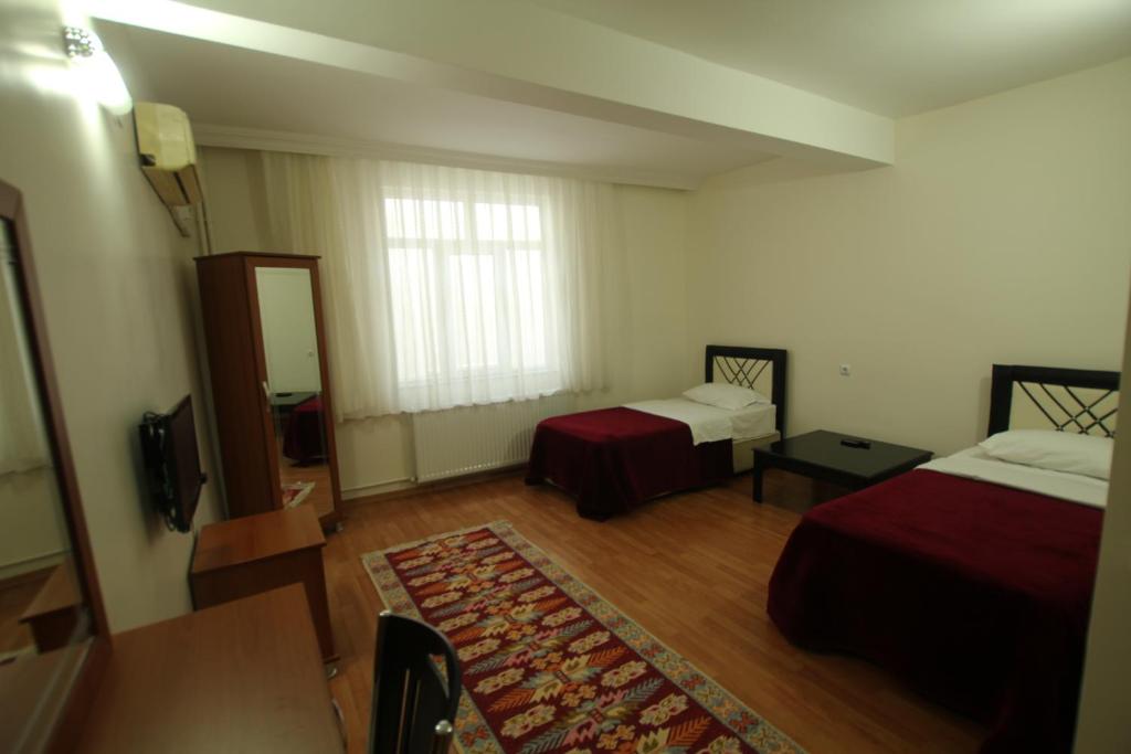 a hotel room with two beds and a mirror at Köprücü Hotel in Diyarbakır