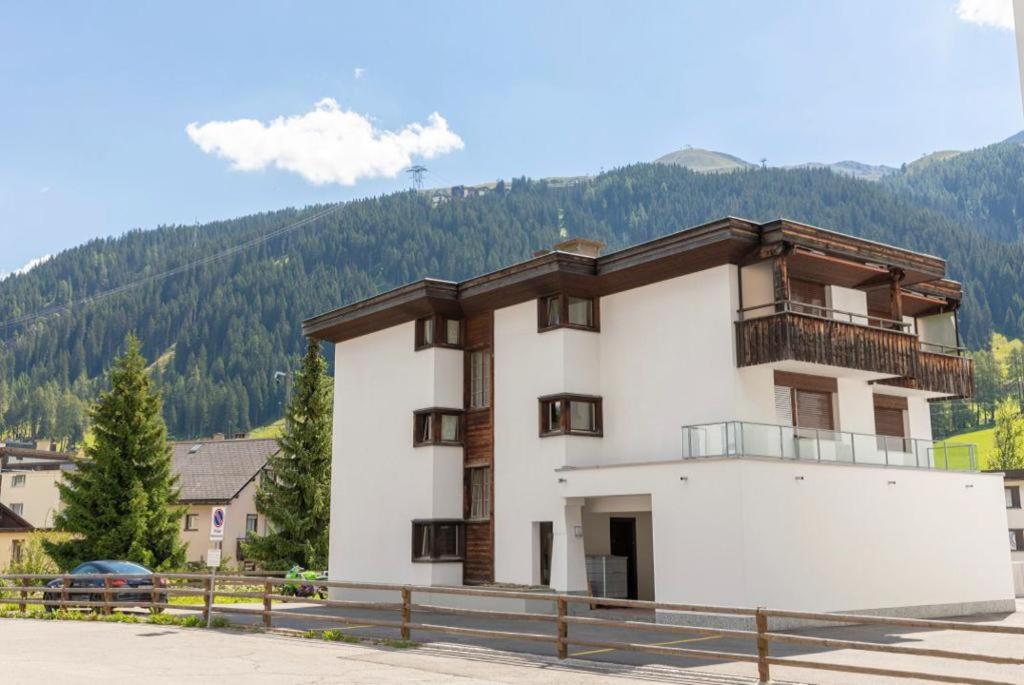 un gran edificio blanco con montañas en el fondo en Agrimonia - möbilierte Ferienwohnung mit Balkon en Davos