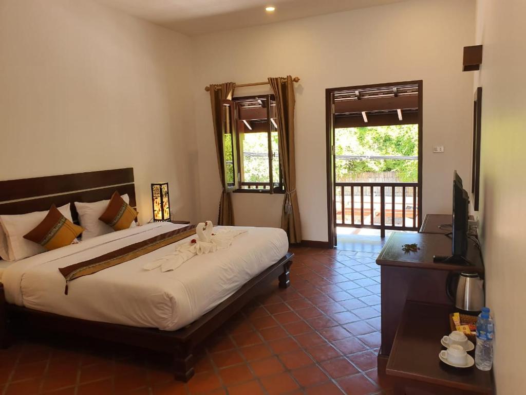 a bedroom with a bed and a television in it at Villa Chitchareune 2 in Luang Prabang