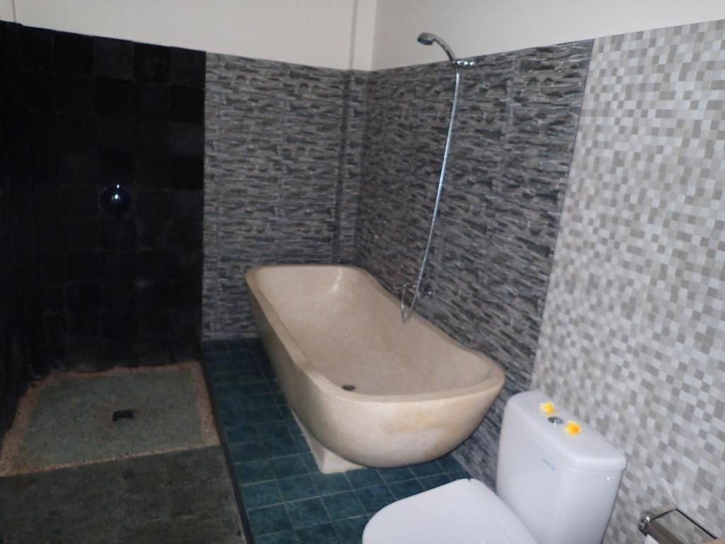 a bathroom with a bath tub and a toilet at Alami Resort, Restaurant and Dive Center in Amed