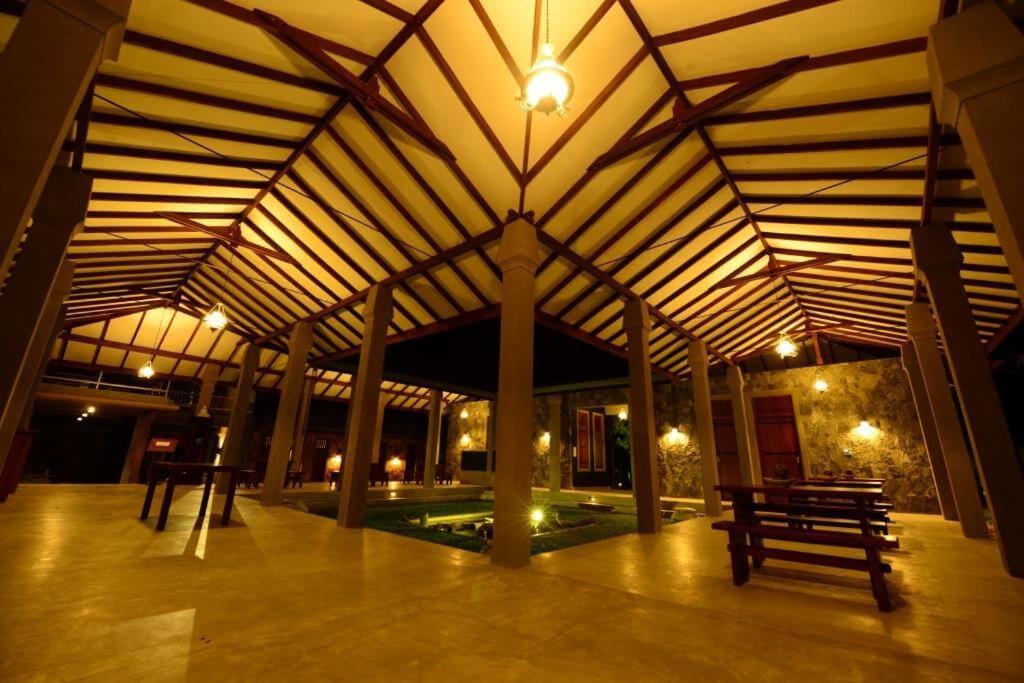 a building with a wooden roof with benches in it at Nil Diya Mankada Safari Lodge in Udawalawe