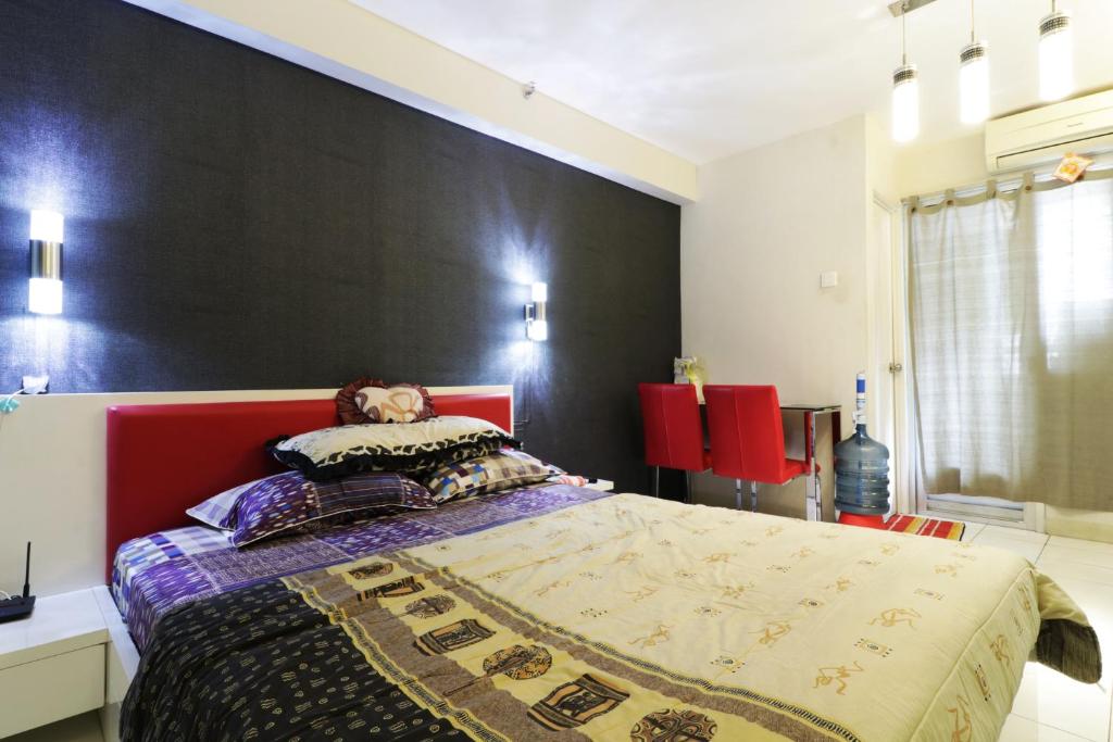 um quarto com uma cama grande e uma cabeceira vermelha em Apartment Kalibata City by Novi em Jakarta