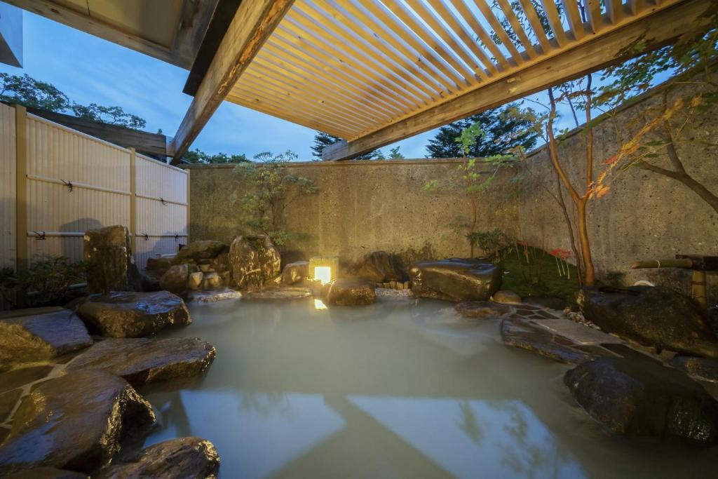 a pool of water with rocks in a garden at Hotel Hanaan in Nikko