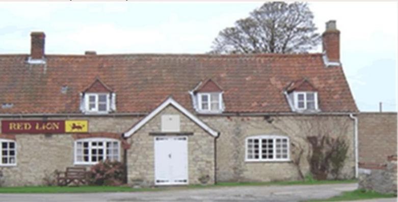 a large brick building with a white door at Red Lion Dunston in Branston