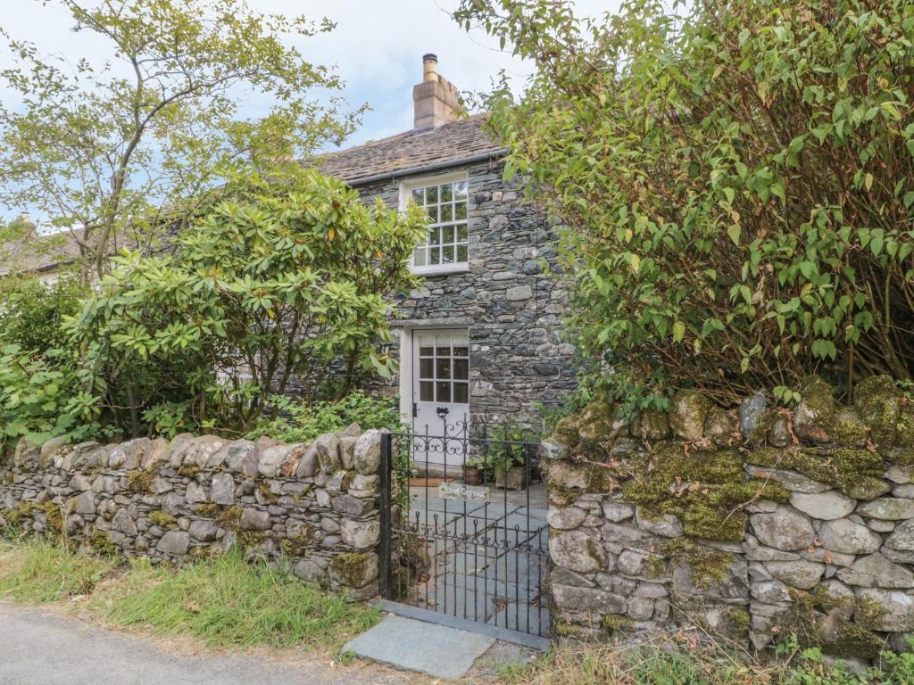 ein altes Steinhaus mit einem Tor und einer Steinmauer in der Unterkunft Stair Cottage in Keswick