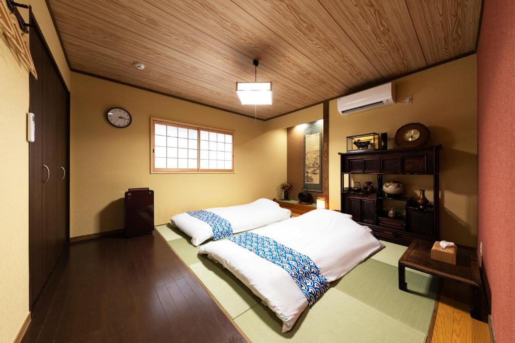 a bedroom with two beds and a wooden ceiling at Shirakabanoyado - Nakamichi in Osaka