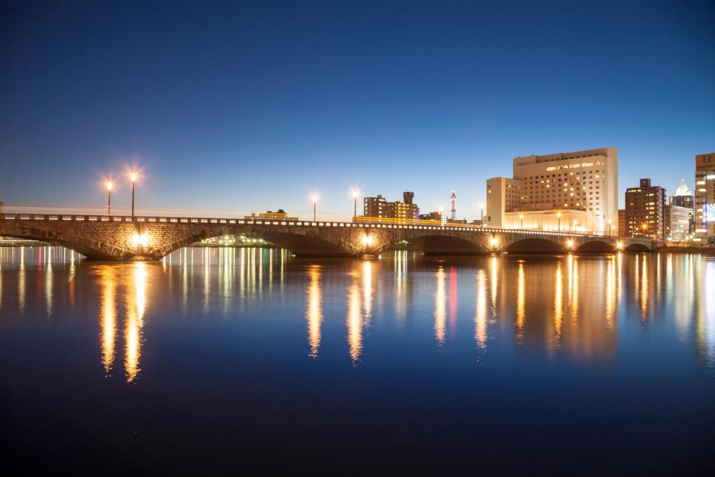 uma ponte sobre a água em uma cidade à noite em Hotel Okura Niigata em Niigata