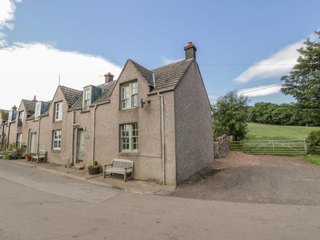 a building with a bench on the side of a street at Near Bank Cottage in Eyemouth