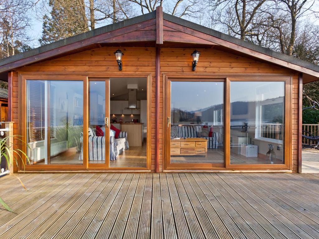 een houten hut met grote glazen deuren op een terras bij Lodge on the Lake in Windermere