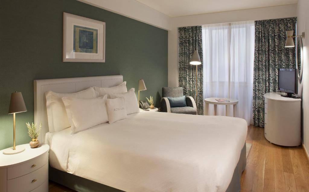 sypialnia z dużym białym łóżkiem i telewizorem w obiekcie Altis Suites Apartamentos Turísticos w Lizbonie