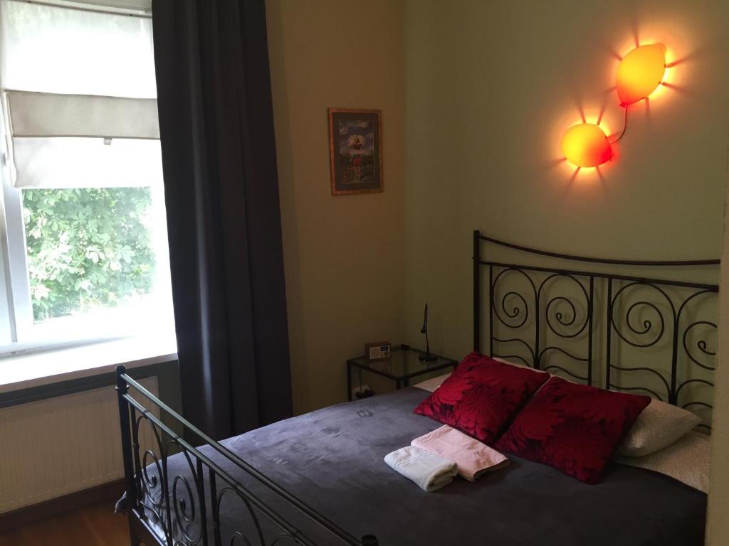 Un dormitorio con una cama con almohadas rojas y una ventana en Apartament PIĘKNA, en Varsovia