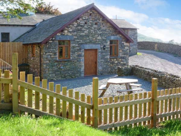 une maison en pierre avec une clôture en bois devant elle dans l'établissement Yew Tree Cottage, à Coniston